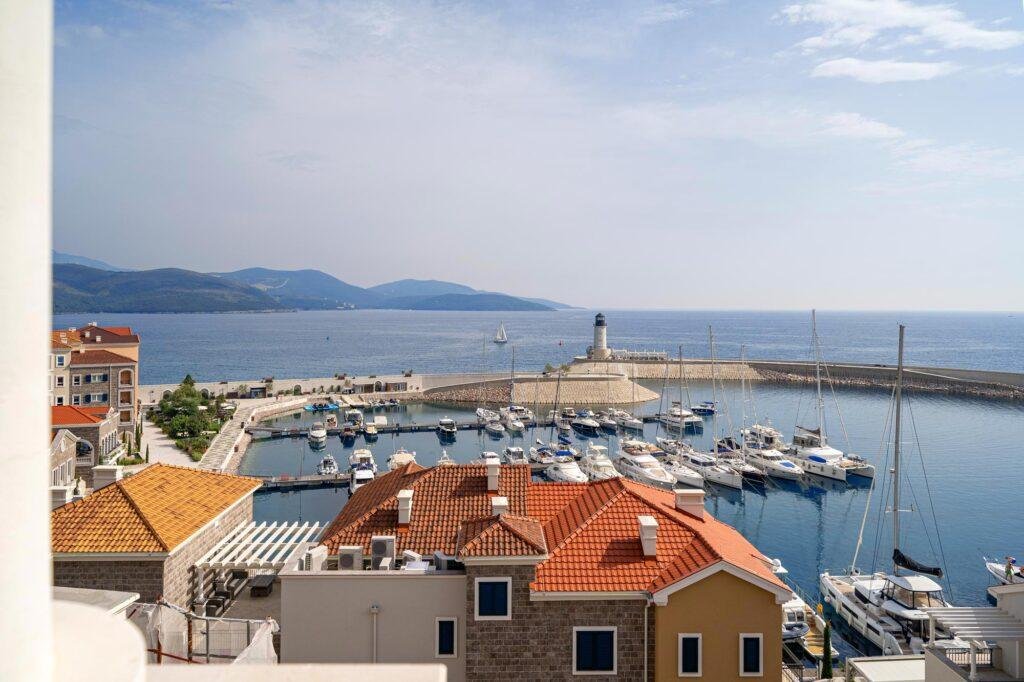prikazani su krovovi zgrada na prvoj liniji u lustici bay, delimicno hotel Chedi, vidi se svetionik, more i jahte koje su uvzane u marini