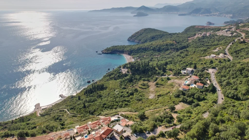 A drone shot showing greenery, available building plots, the sea, and the main coastal highway.