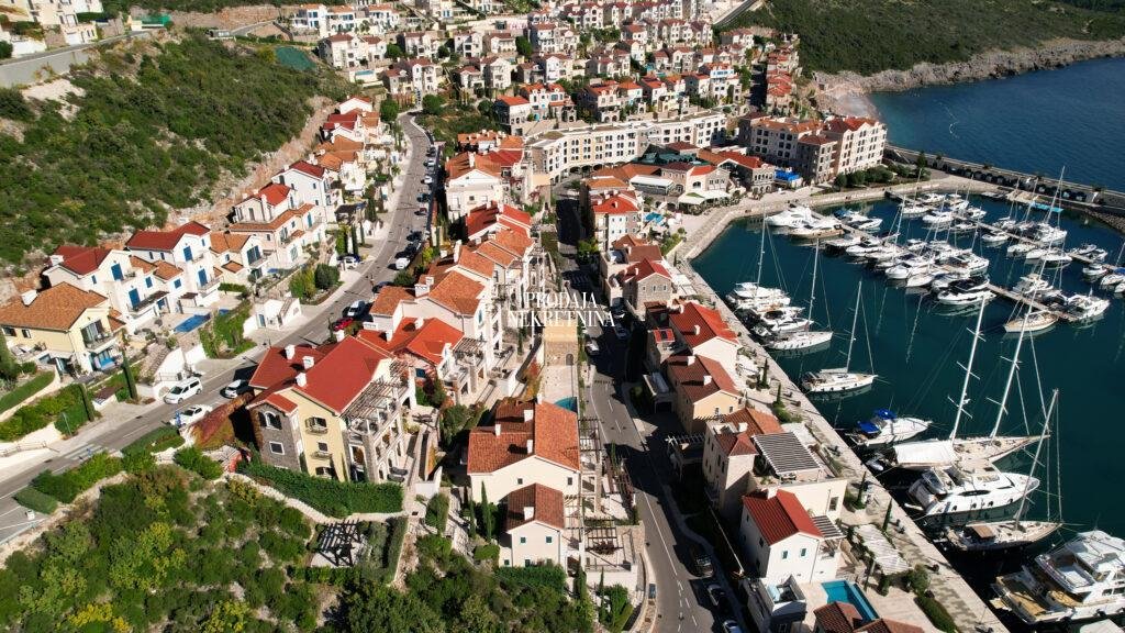 a part of marina village, stone facade buildings, greenery, marina for yachts, promenade and sea