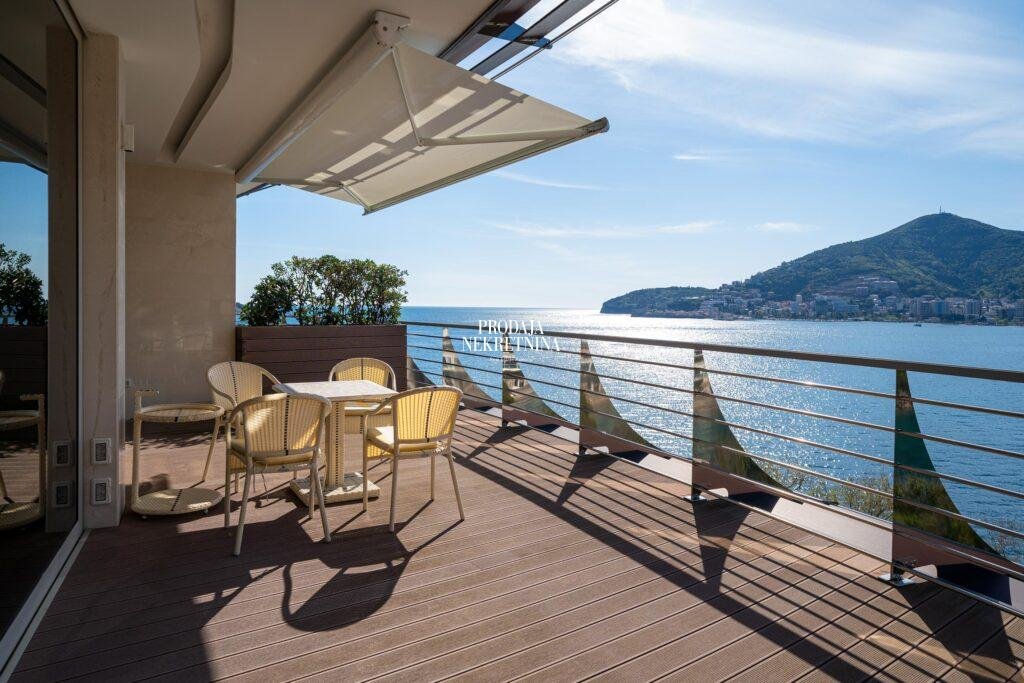 apartment balcony in dukley gardens residential complex. it shows the decking, some greenery as  partition to anothe apartment, tend and amayzing view to the sea and the city of budva on the other side